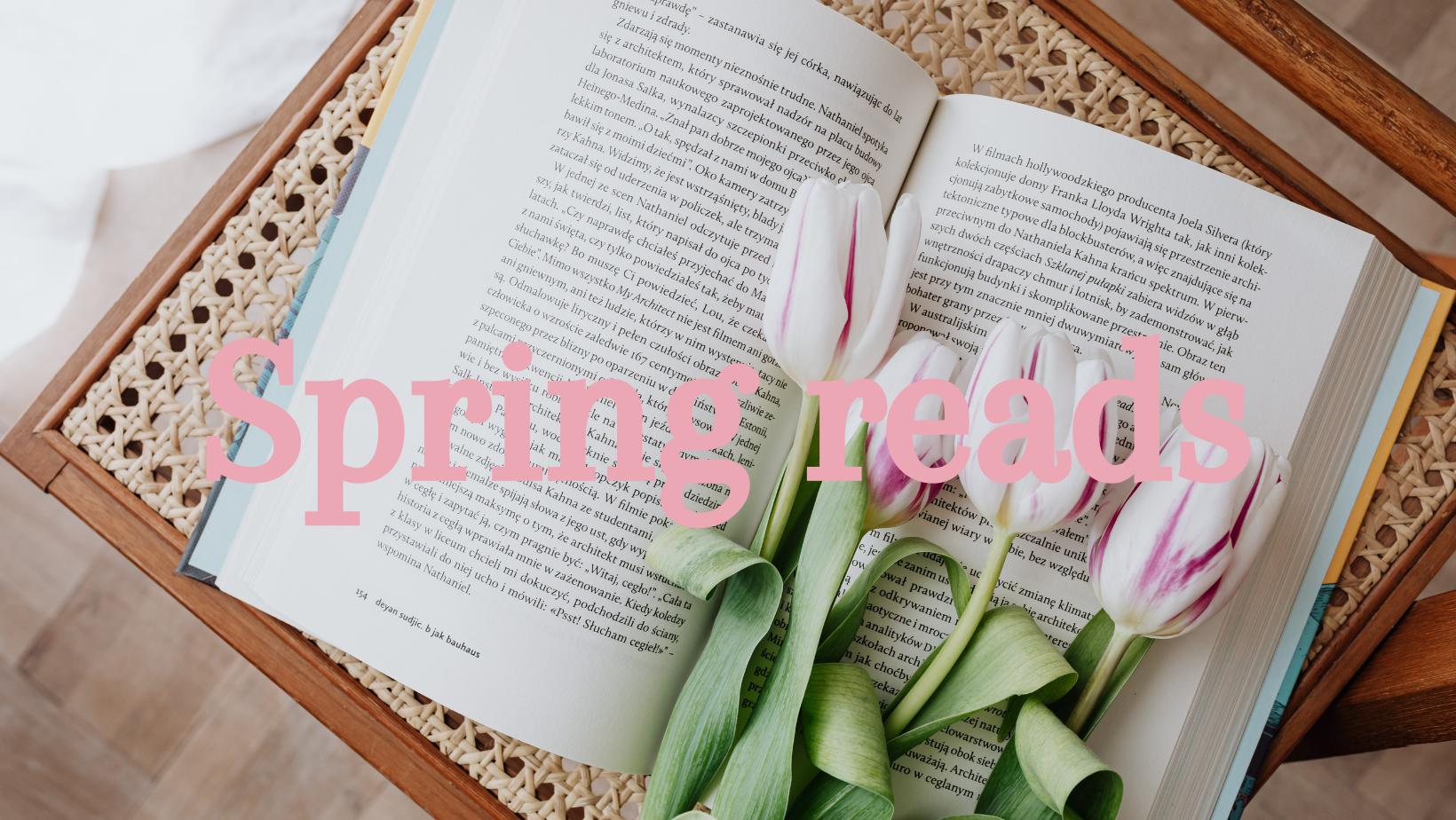 an open book on a chair with pink tulips laying on the open book