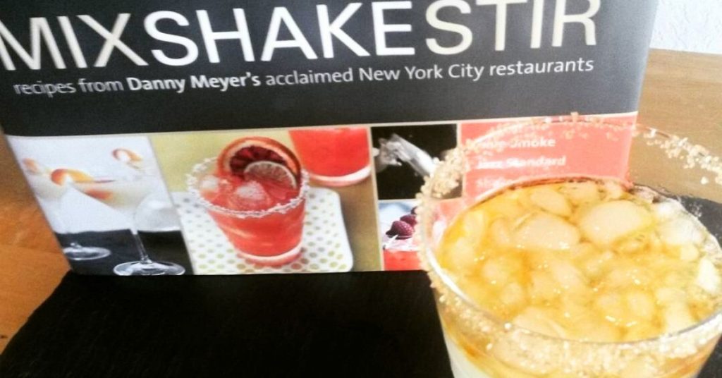 a cocktail book and a drink
