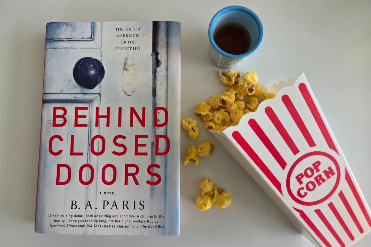 the book Behind Closed Doors with spilled popcorn and a shot of whiskey